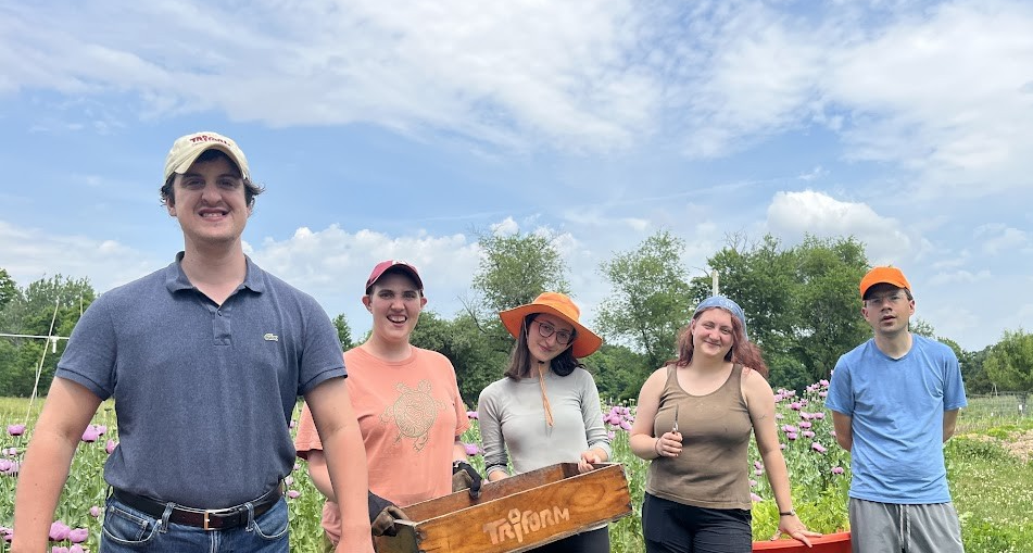 A group of people stand together in a garden, smiling.