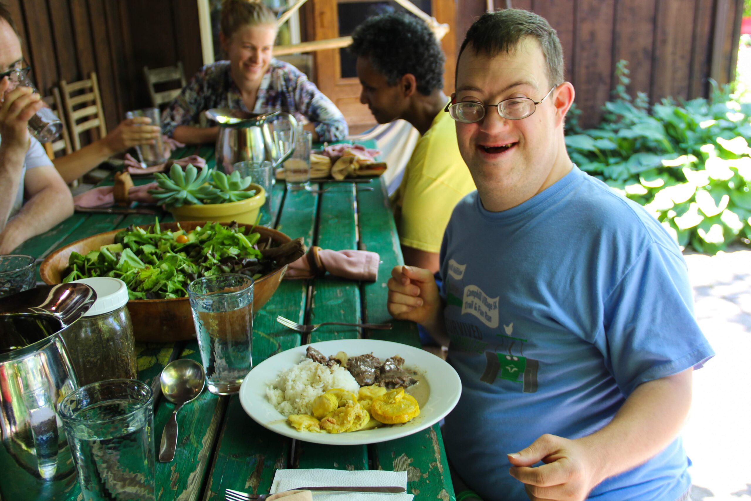 Camphill Village residents eating a meal together outdoors.