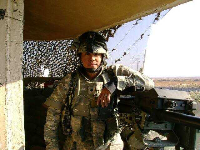 Julius in full military gear leaning on a machine gun