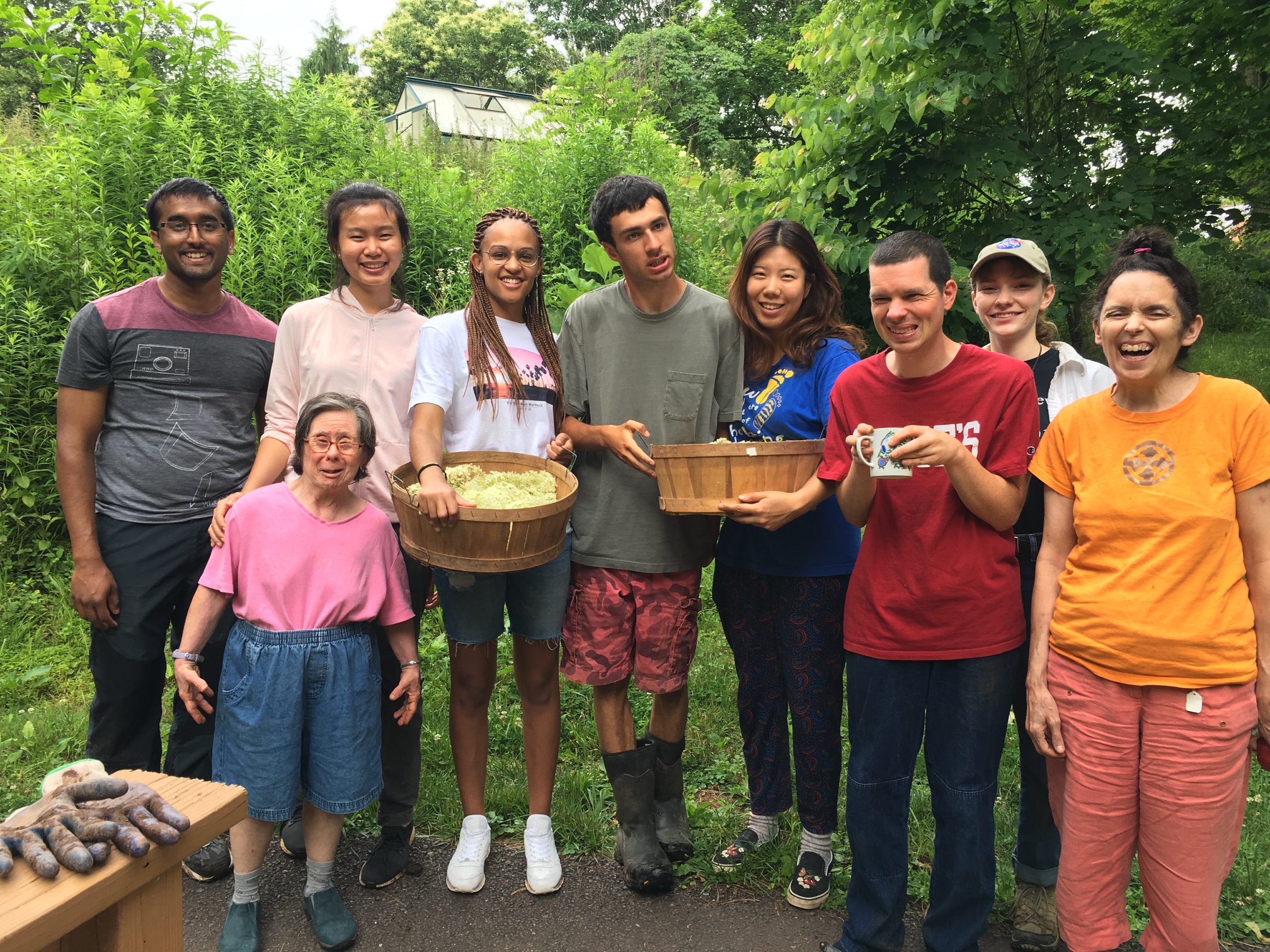A group of people stand together and smile for the camera, holding baskets of food.