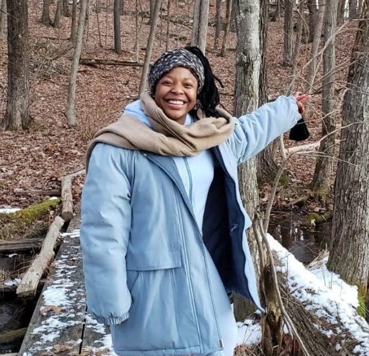 Lisa standing on a snowy bridge in the forest, smiling at the camera