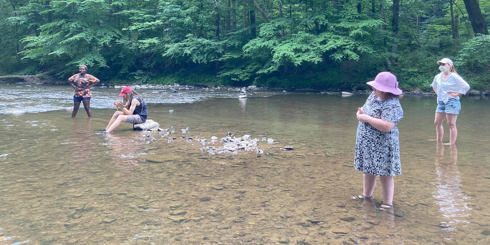 People exploring a wide, shallow river bed