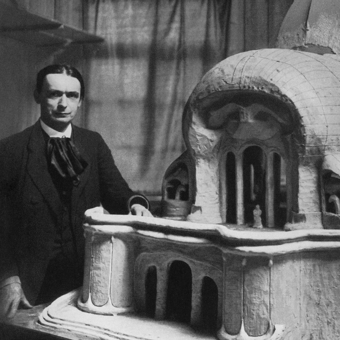 A black-and-white photo of Rudolf Steiner standing next to a model building