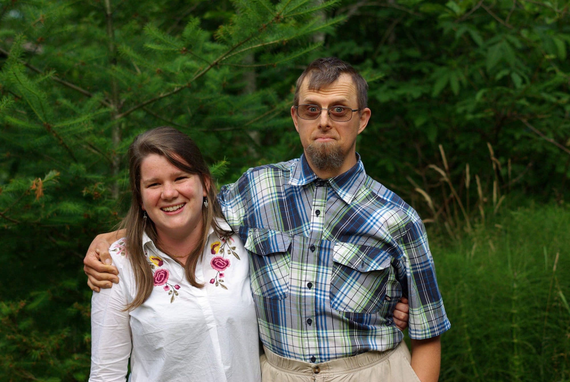 Two people hug each other and smile at the camera