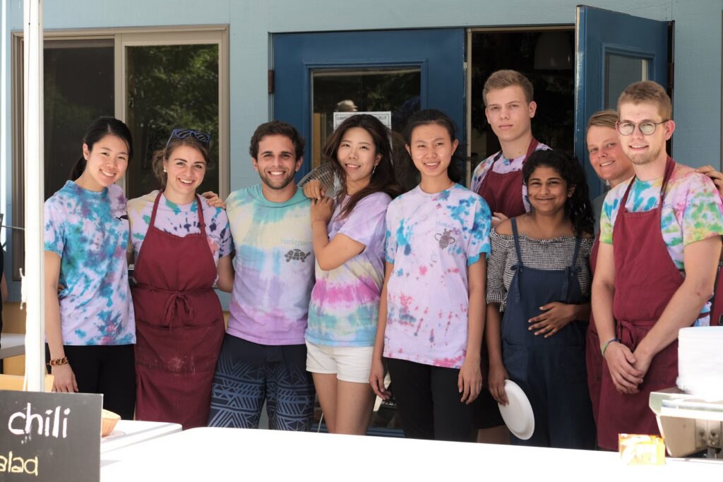 A group of people in aprons and tie-dye shirts posing together and smiling for the camera.