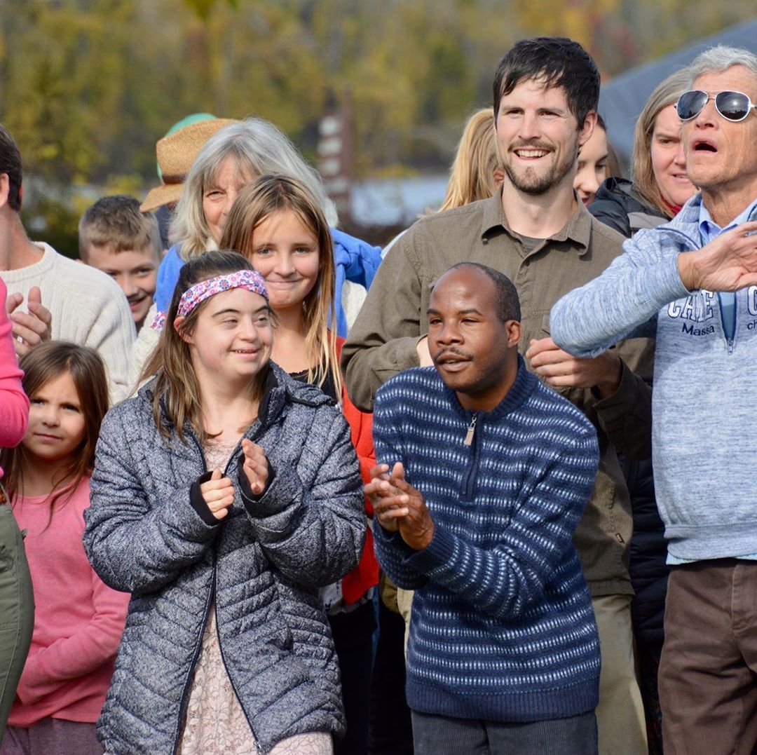 A group of people outdoors, with two people in front clapping