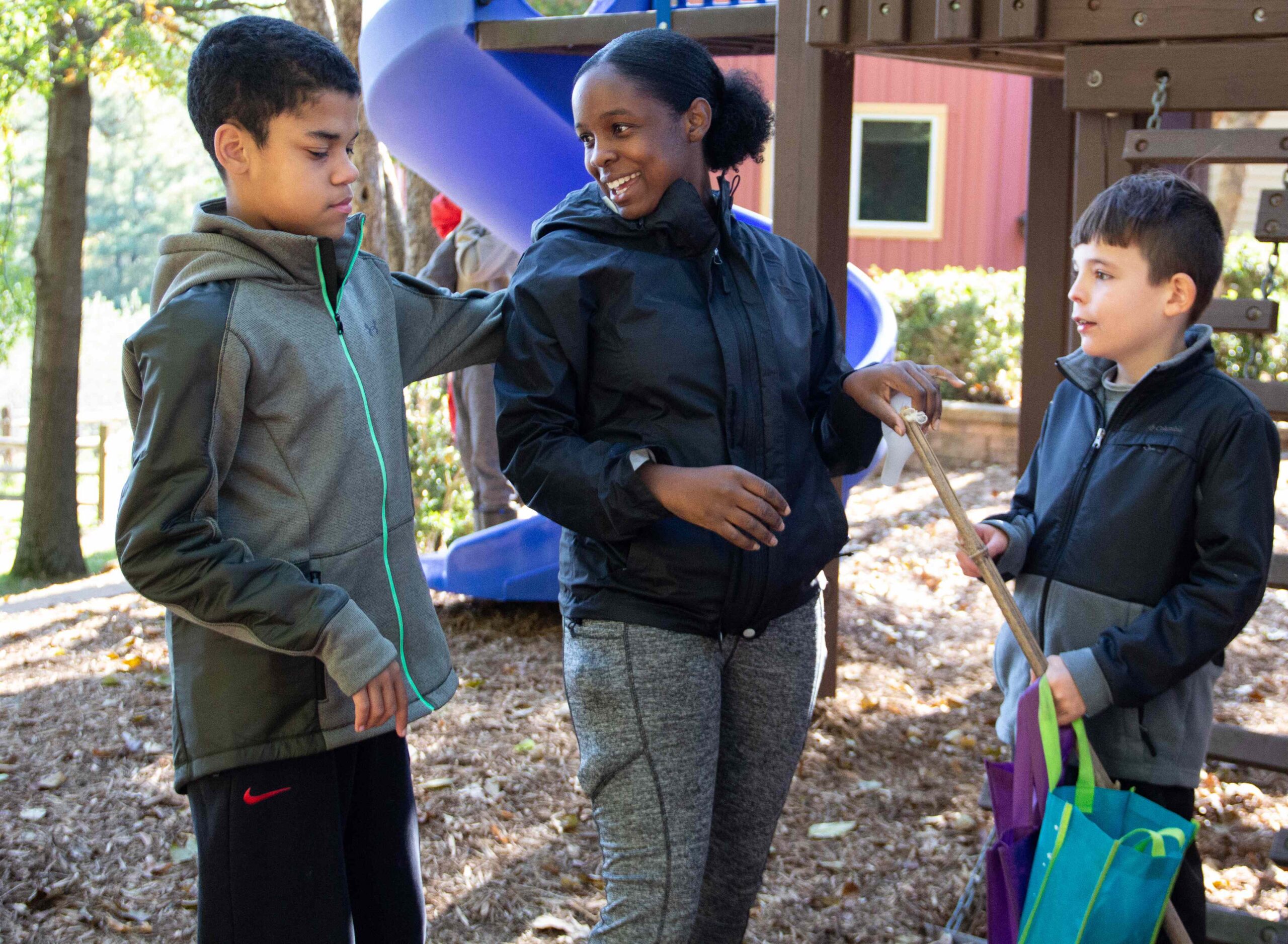 A young woman and two boys outside on a playground