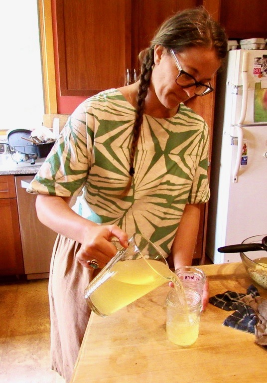 A woman pours elderflower cordial into cans