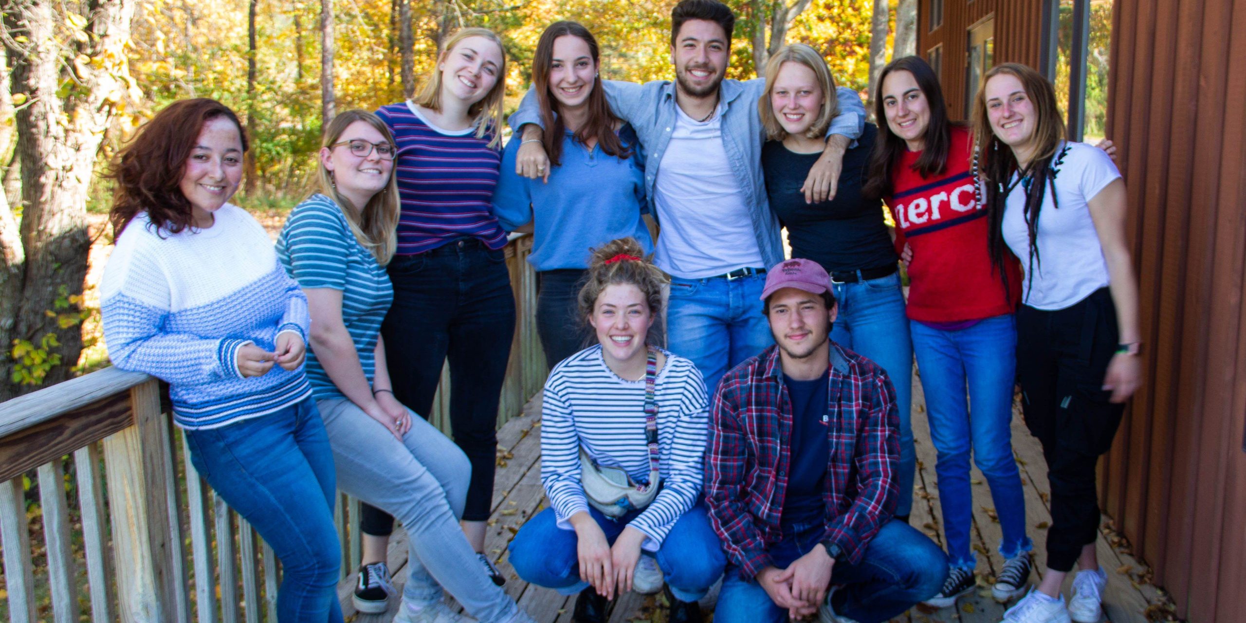 A group of college grads in the Camphill College Loan Support program standing together on a porch and smiling for the camera together