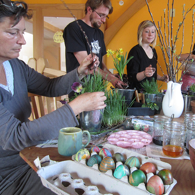 People dying Easter eggs and creating centerpieces with spring buds and daffodils