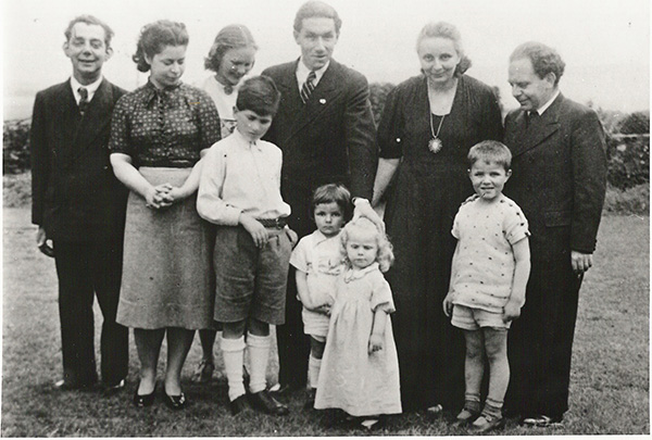 A black-and-white photo of a group of people of all ages standing together outside.