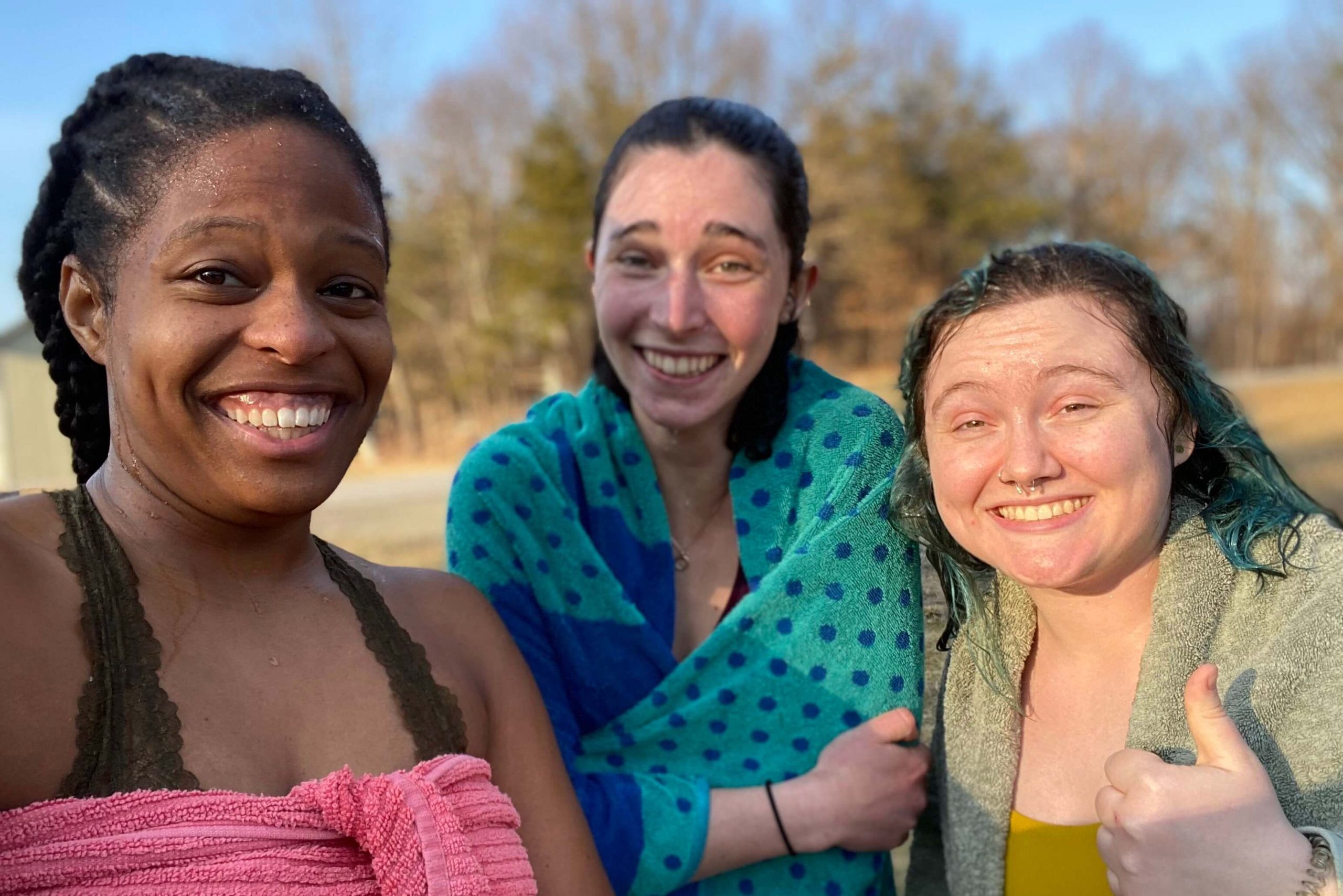 Gabi and two friends smile for a selfie while wrapped in towels. They are drying off after having gone swimming.