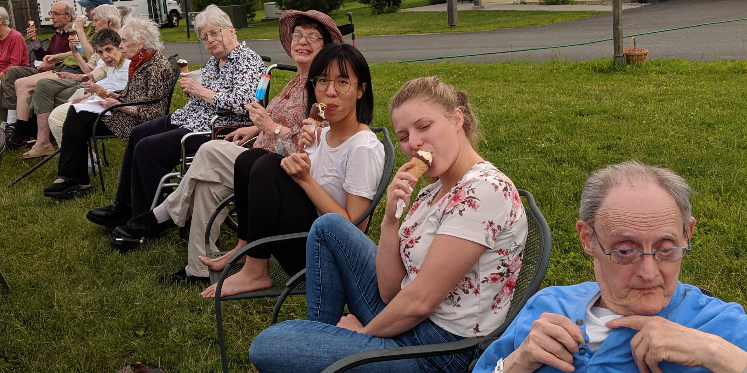 People of all ages sit in chairs outside, enjoying ice cream together