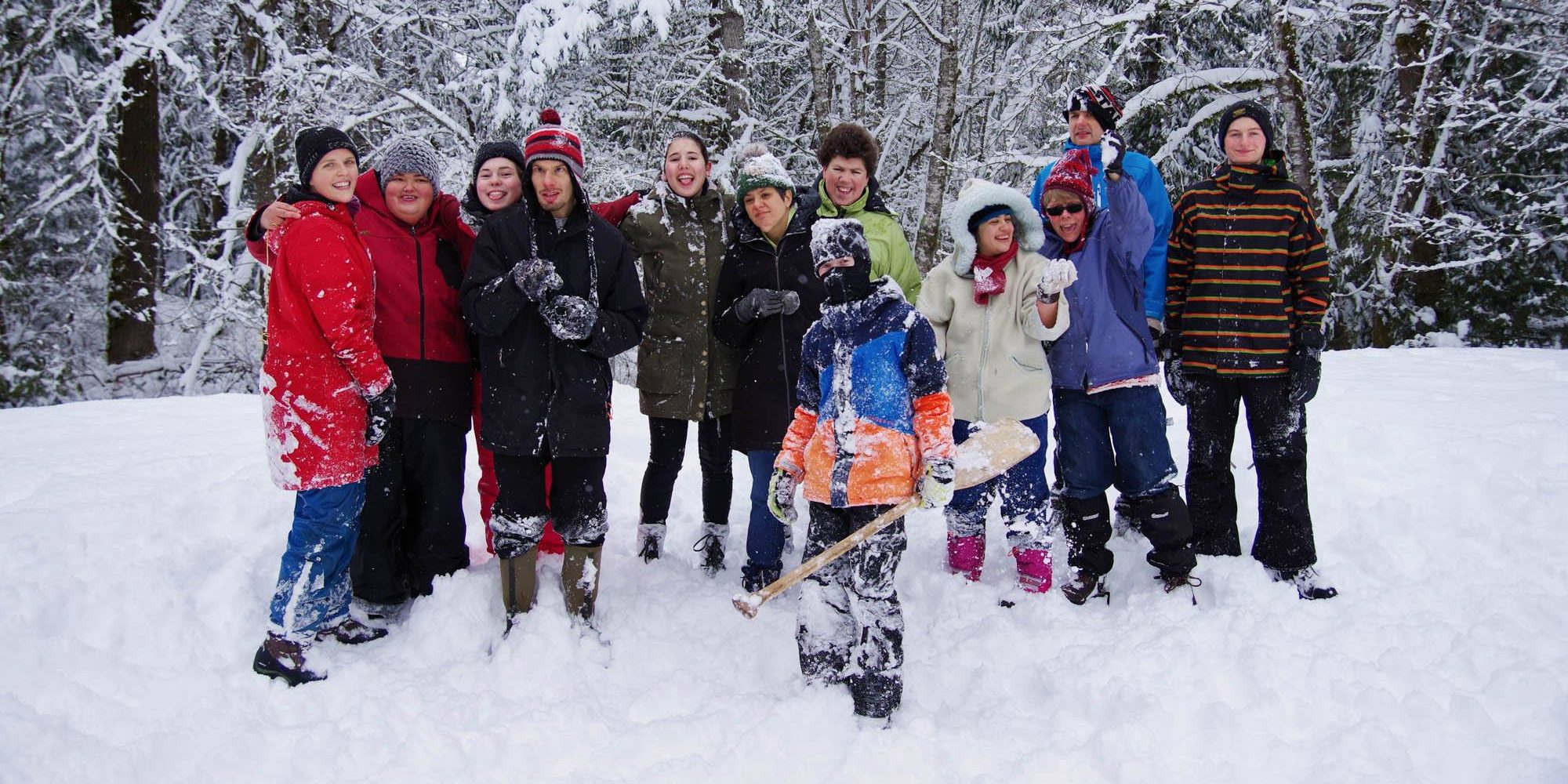 A group of people playing and posing in the snow.