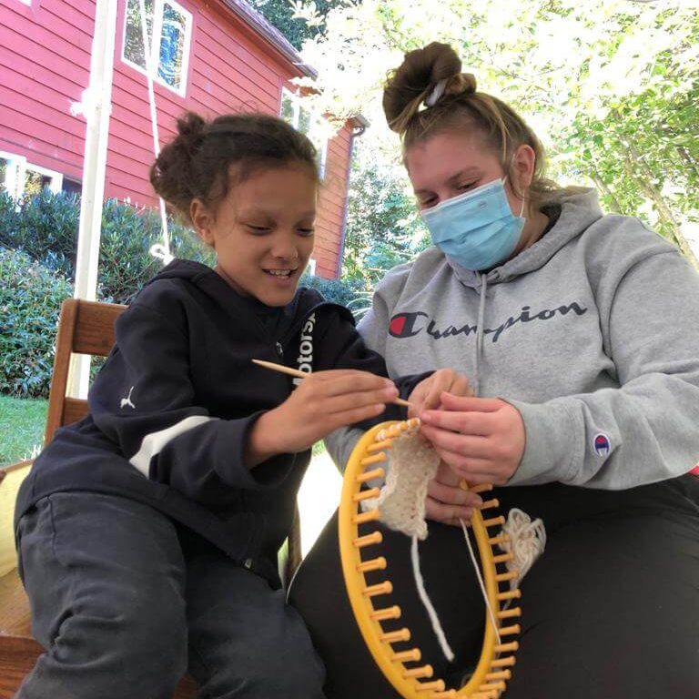 Two people work together on a circular loom.
