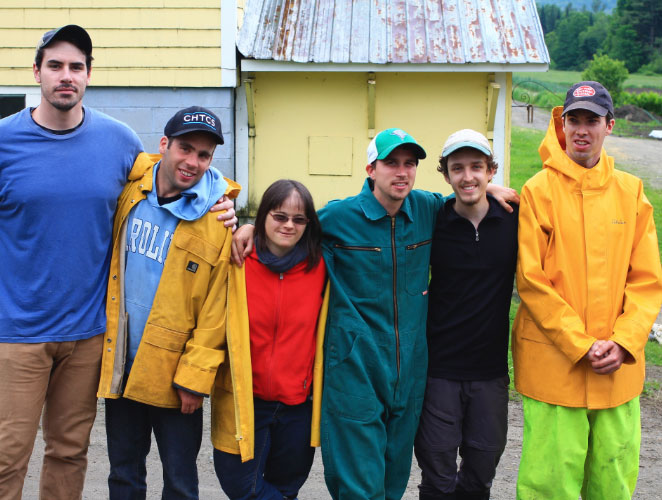 A group of people in outdoor clothing hugging each other and posing for the camera