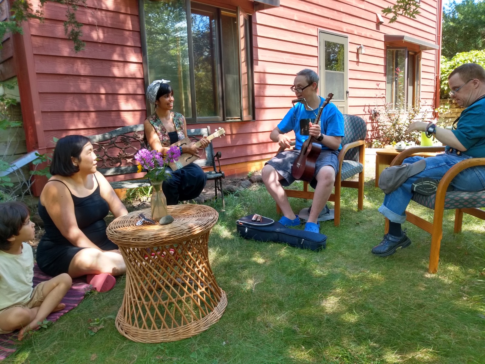 People sitting outdoors playing instruments together