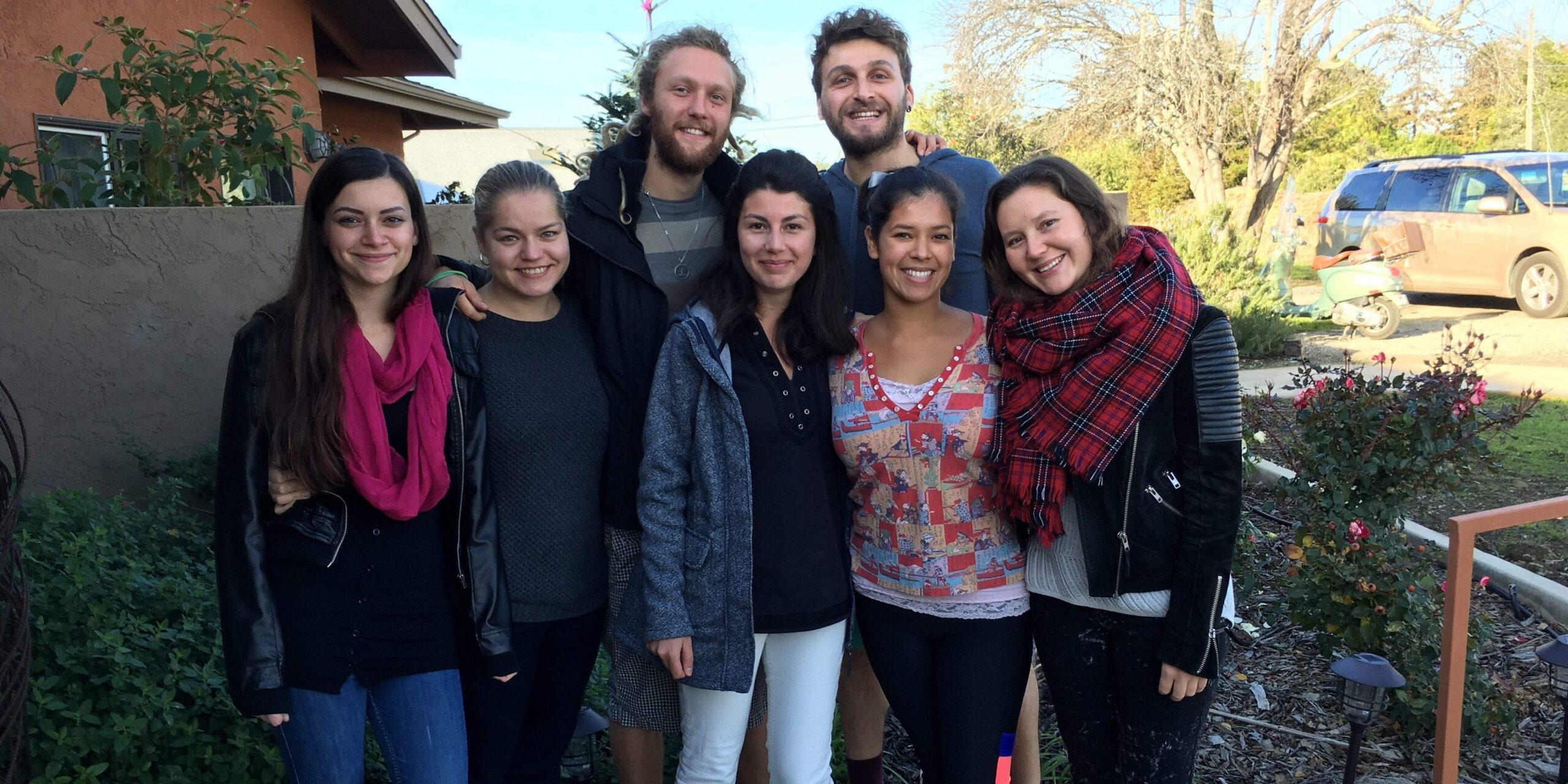 A group of people smiling and standing together, looking at the camera.