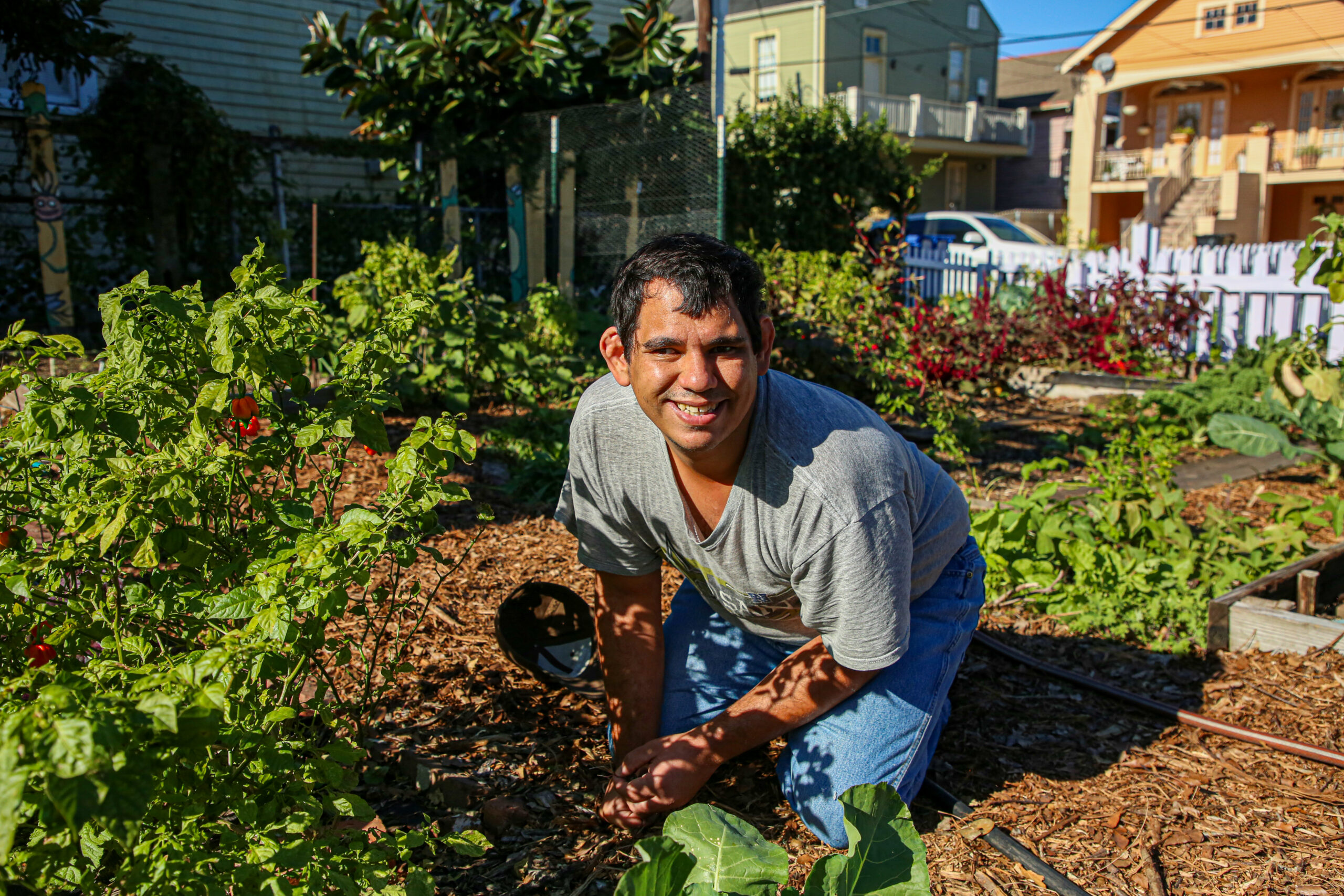 A gardener smiles among the leaves in a garden on a sunny day in New Orleans