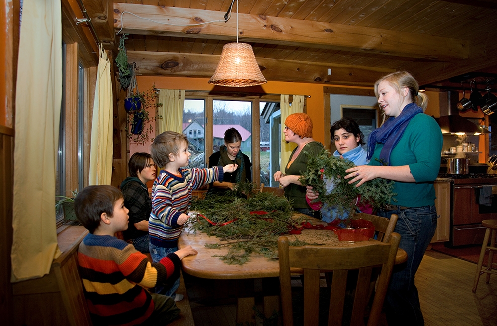 People of all ages work together to make wreaths at a kitchen table
