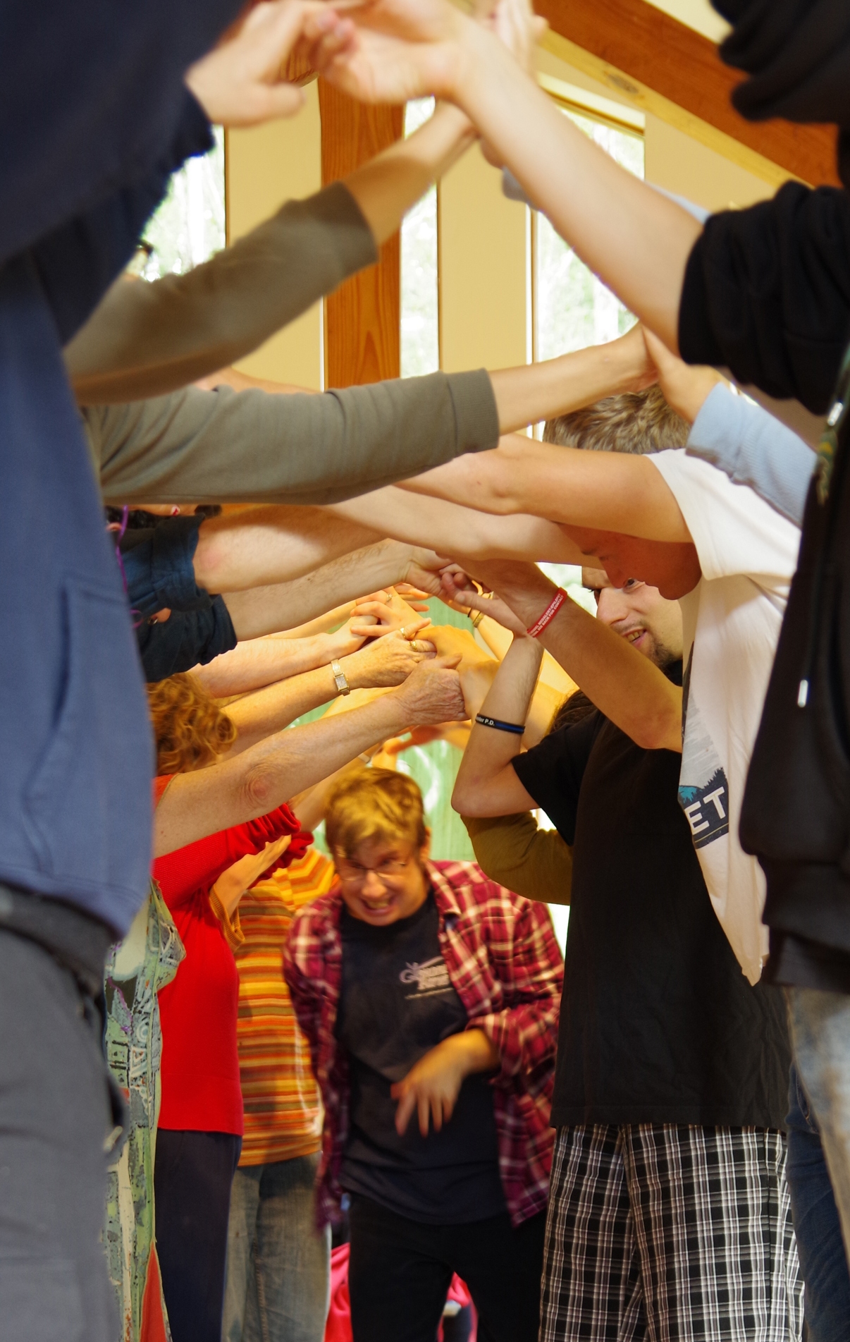 People hold up their hands to make a bridge as another person runs under it.