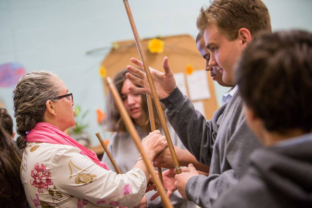 An instructor hands out sticks to young adults