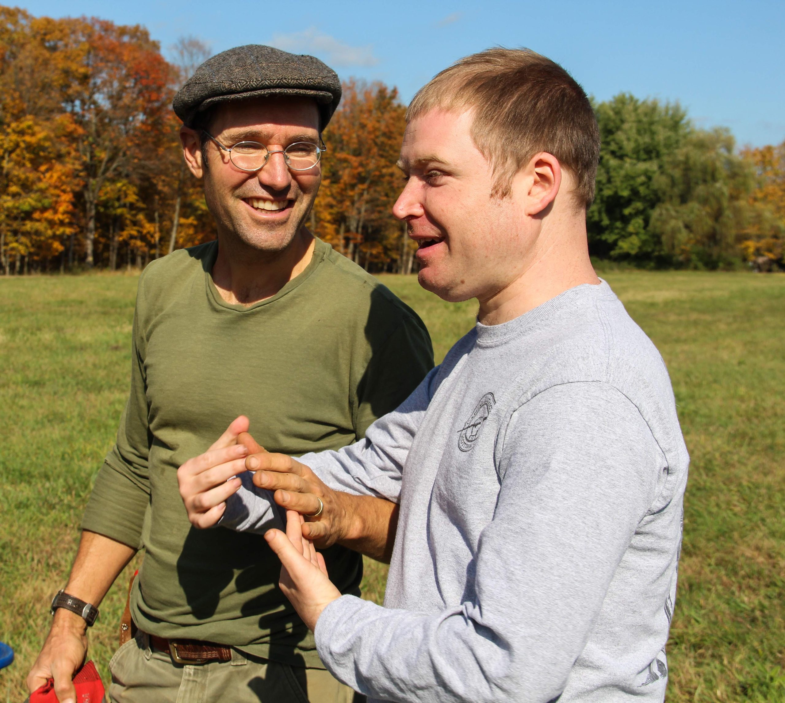 Two men talking and smiling outside in a field