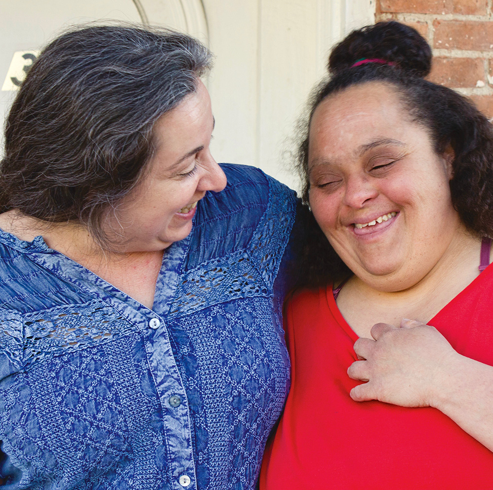 Two women hug and smile at each other