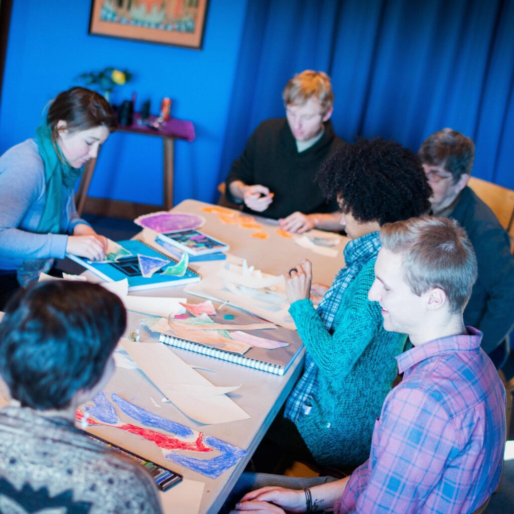 People seated around a table creating paper art.