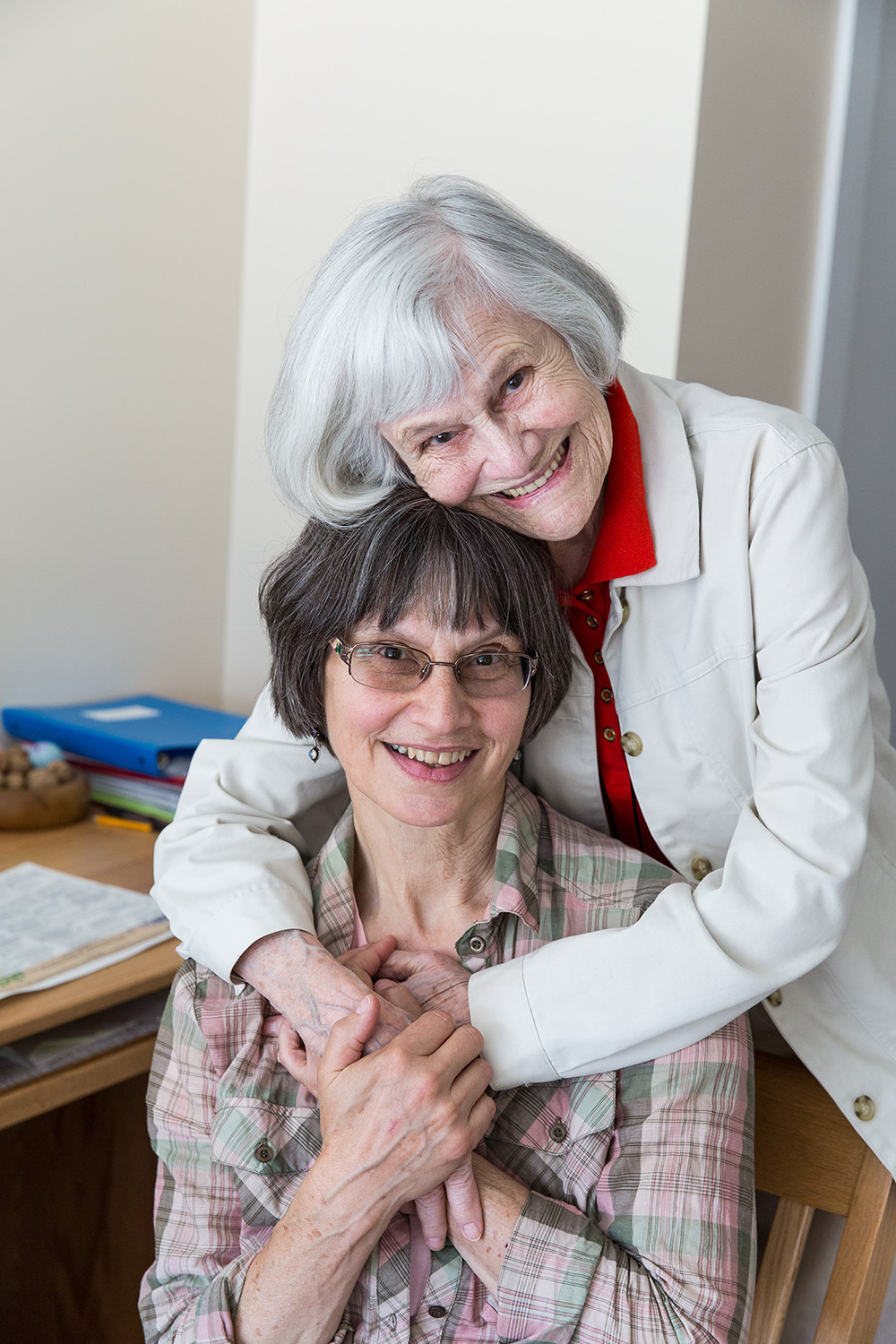 Two older women hugging each other and smiling at the camera