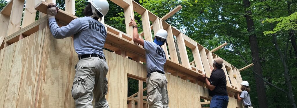 Several people in hard hats work on building a house