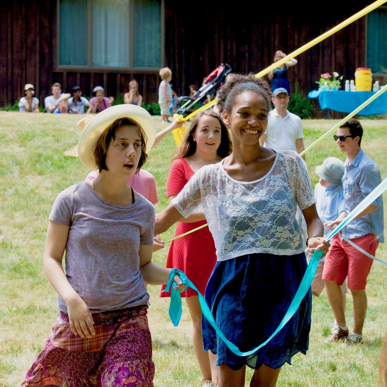 People of all ages dance around a may pole