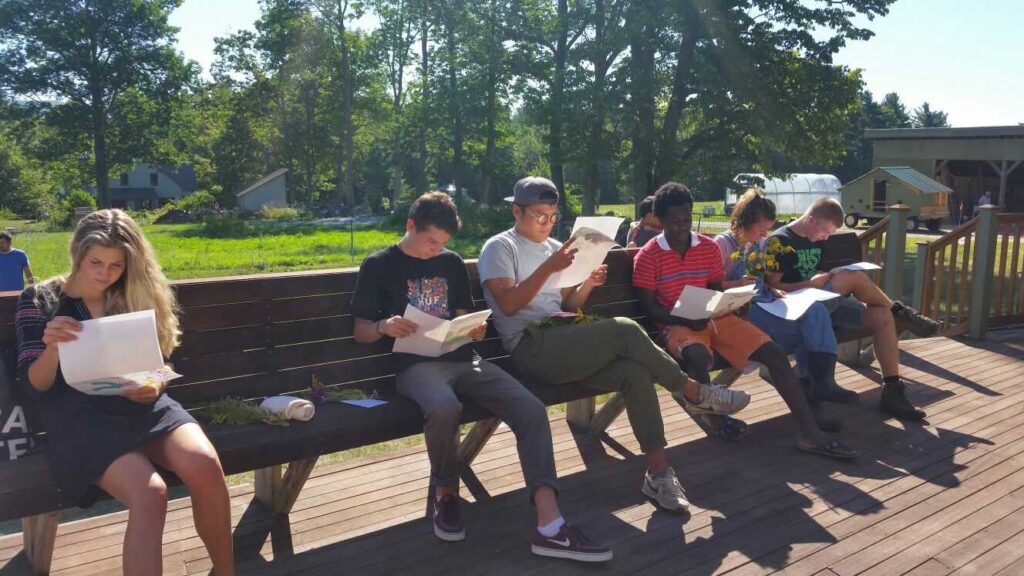 A group of volunteers sit on a bench reading letters.