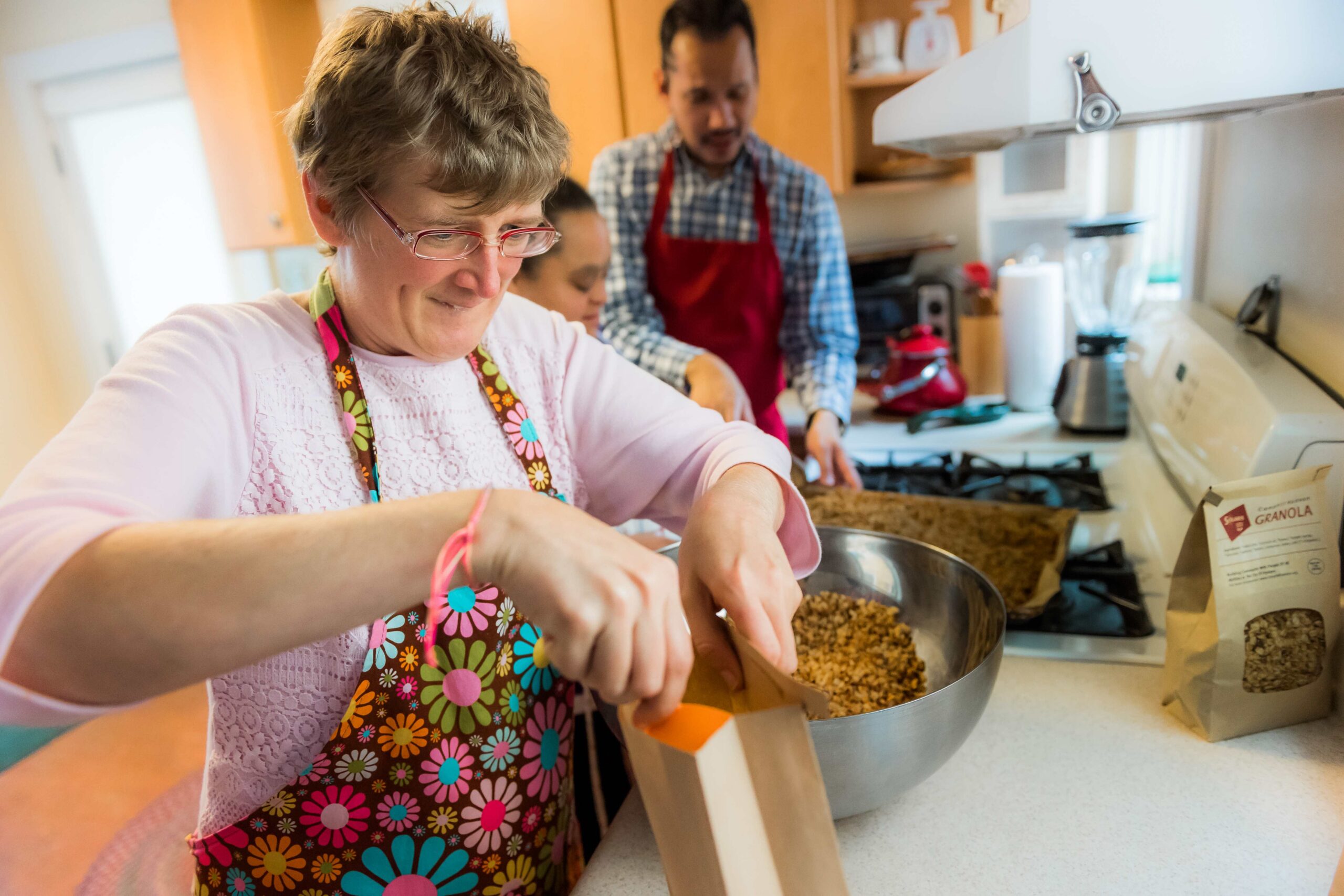 Three people making granola together in a kitchen.