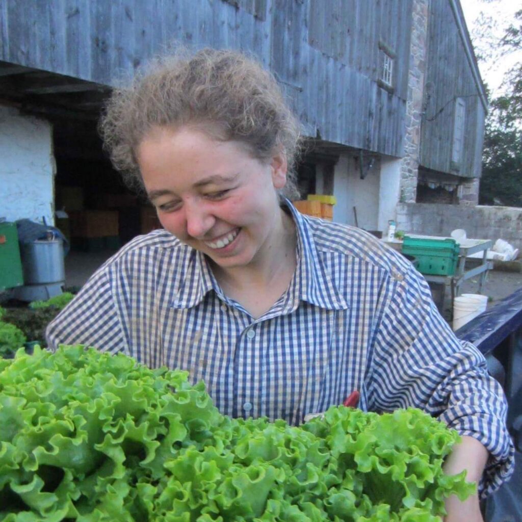 A woman beams over the armful of lettuce she is holding