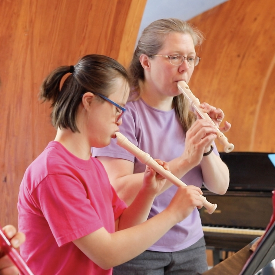 A girl and a woman play recorders together