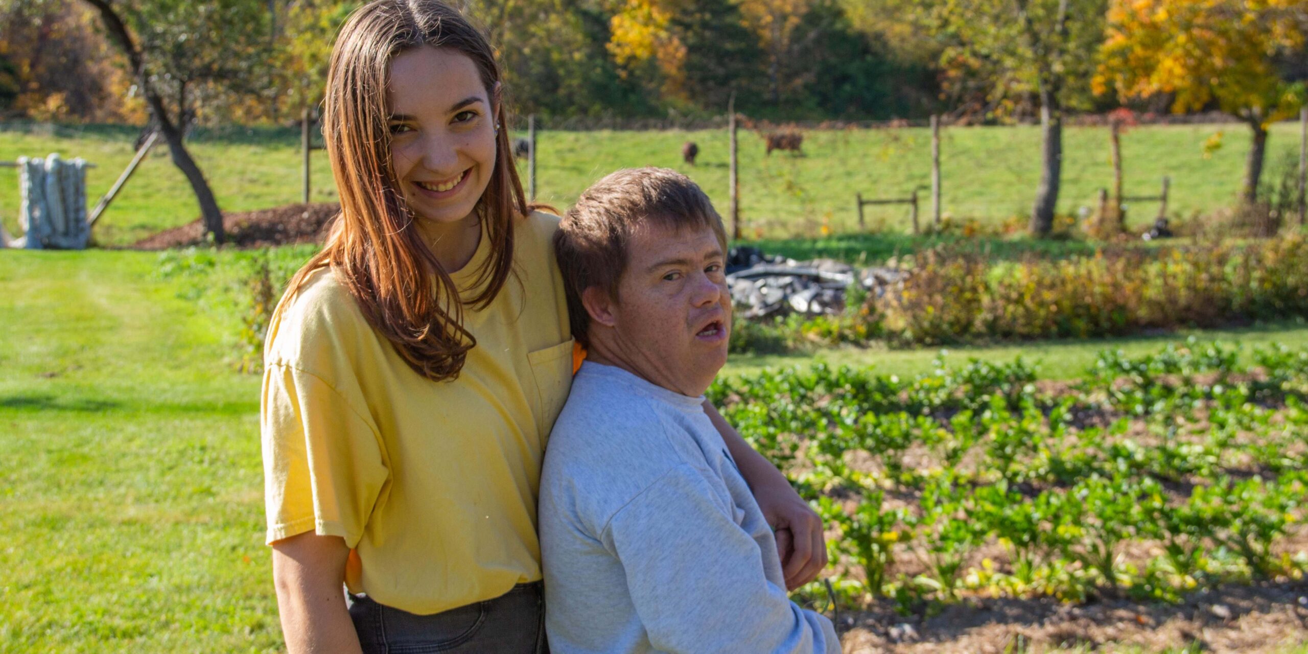 Two people hug in front of a garden