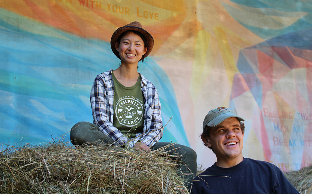 Two farmers sit together on top of hay bales.