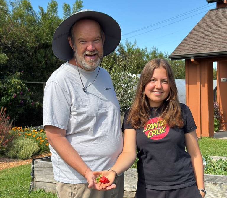 Johnathan and Sarah standing in front of the Marimi Barn holding a strawberry